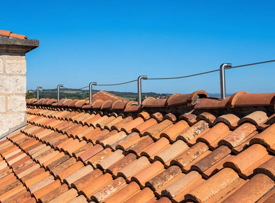 Operaio agganciato con imbracatura alla linea vita sul colmo del tetto