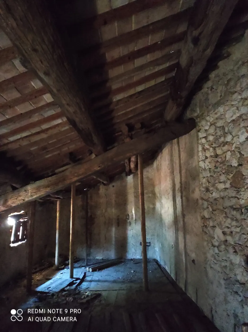 Parete interna in sasso e mattoni sotto le travi del solaio