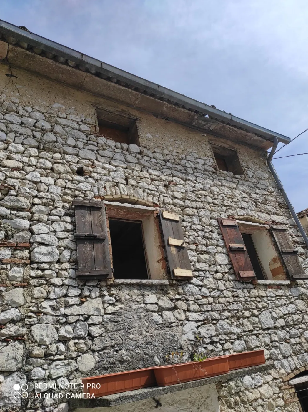 Facciata in sasso a vista con finestre e scuri in legno
