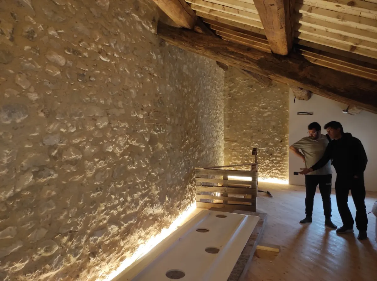 Interno recuperato con parete in sasso a vista e travi in legno